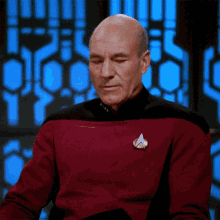A Bald Man Wearing A Red Sweater With A Star Trek Logo On His Chest GIF