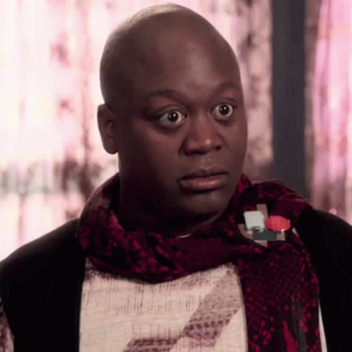A Bald Man Wearing A Scarf And A Snake Print Shirt Looks Surprised GIF