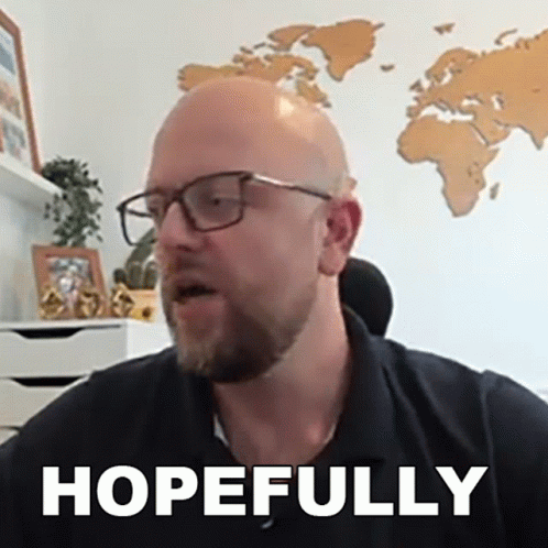 A Bald Man Wearing Glasses And A Black Shirt Says Hopefully In Front Of A Map Of The World . GIF