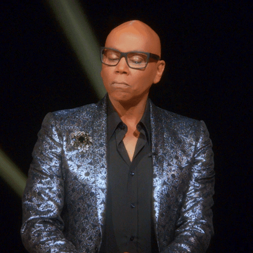A Bald Man Wearing Glasses And A Blue Jacket Looks Down GIF