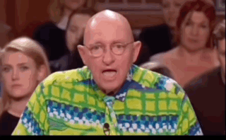 A Bald Man Wearing Glasses And A Colorful Shirt Is Standing In Front Of A Crowd . GIF
