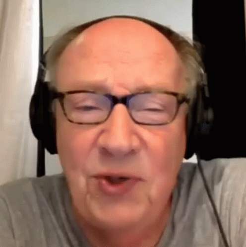 A Bald Man Wearing Glasses And Headphones Is Talking To Someone . GIF