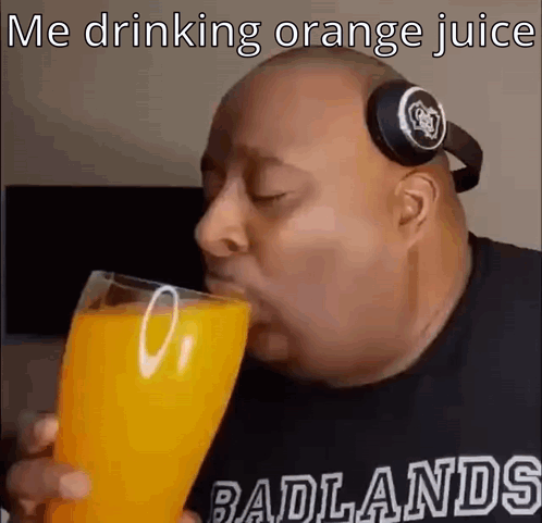 A Bald Man Wearing Headphones Is Drinking Orange Juice . GIF