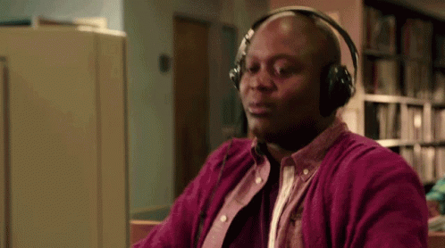 A Bald Man Wearing Headphones Is Sitting In Front Of A Computer . GIF