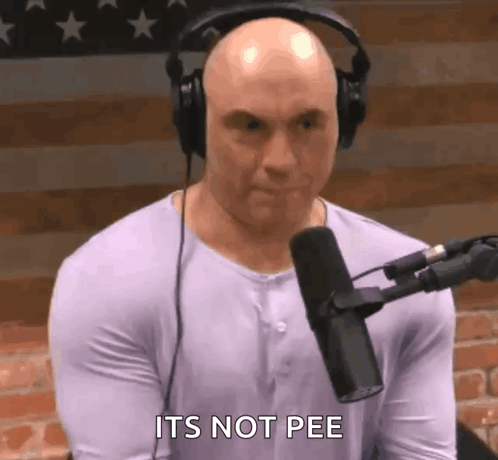 A Bald Man Wearing Headphones Is Sitting In Front Of A Microphone And Says It 'S Not Pee . GIF