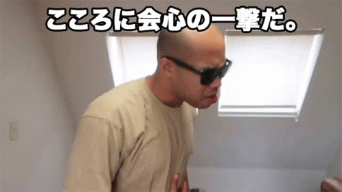A Bald Man Wearing Sunglasses And A Tan Shirt Is Standing In Front Of A Window With Chinese Writing Behind Him GIF