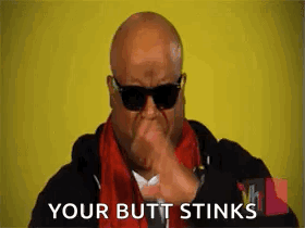 A Bald Man Wearing Sunglasses Is Covering His Mouth With His Hand . GIF