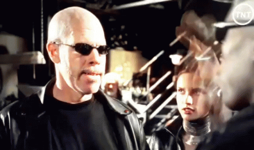 A Bald Man Wearing Sunglasses Is Standing Next To A Woman GIF