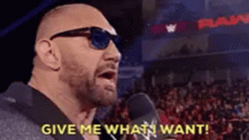 A Bald Man Wearing Sunglasses Is Talking Into A Microphone And Says `` Give Me What I Want '' . GIF