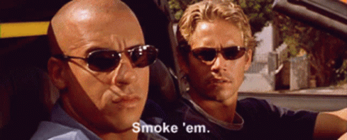 A Bald Man Wearing Sunglasses Says " Smoke 'Em " While Another Man Looks On GIF
