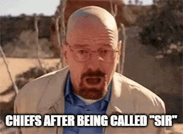 A Bald Man With A Beard And Glasses Is Standing In The Desert And Talking . GIF