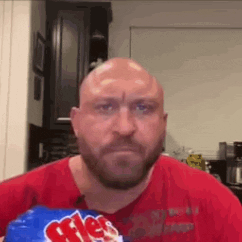 A Bald Man With A Beard Is Eating A Bag Of Mrs. Potato Chips . GIF
