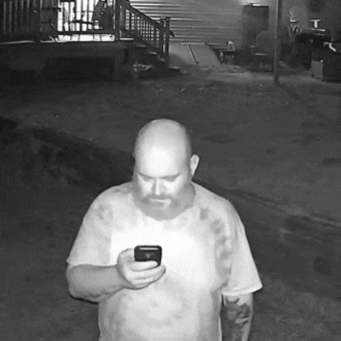 A Bald Man With A Beard Is Holding A Cell Phone GIF