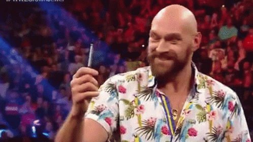A Bald Man With A Beard Is Holding A Cell Phone In Front Of A Crowd Of People . GIF