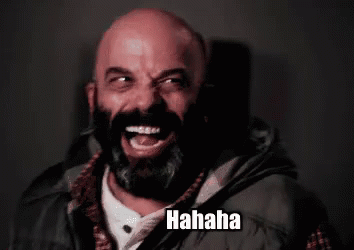 A Bald Man With A Beard Is Laughing While Wearing A Vest . GIF
