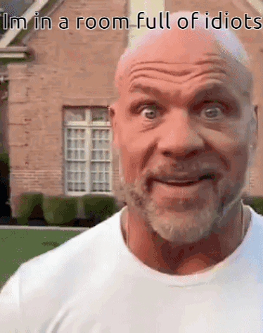 A Bald Man With A Beard Is Making A Funny Face In Front Of A House . GIF