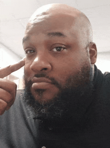 A Bald Man With A Beard Is Pointing To His Forehead GIF