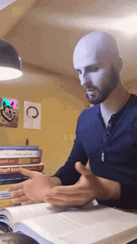 A Bald Man With A Beard Is Reading A Book In Front Of A Stack Of Books . GIF