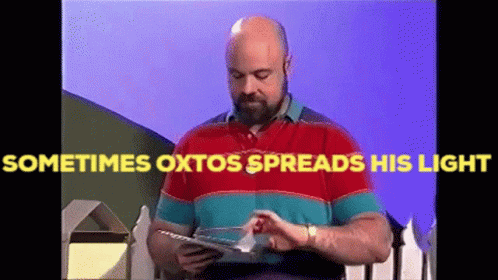 A Bald Man With A Beard Is Reading A Book With The Words Sometimes Oxtos Spreads His Light Above Him GIF