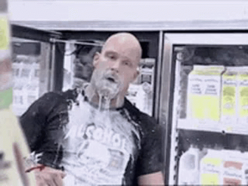 A Bald Man With A Beard Is Standing In Front Of A Refrigerator In A Store . GIF