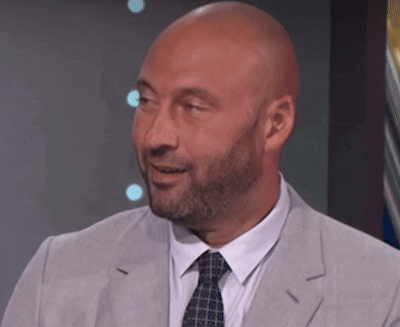 a bald man with a beard is wearing a grey suit and tie