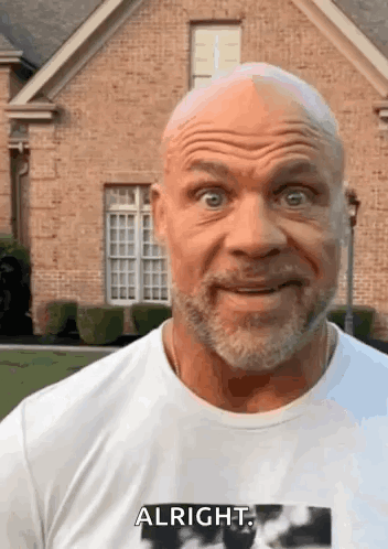 A Bald Man With A Beard Is Wearing A White Shirt That Says Alright GIF