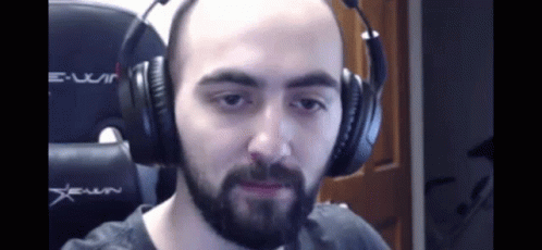 A Bald Man With A Beard Is Wearing Headphones And Making A Funny Face . GIF