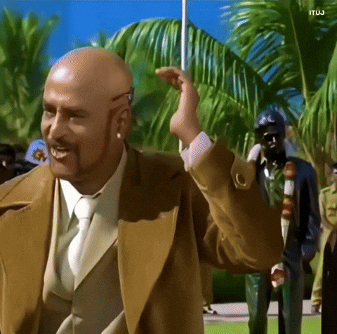 A Bald Man With A Beard Wearing A Tan Suit And Tie GIF