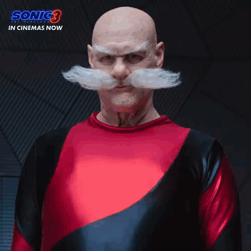 A Bald Man With A Mustache And A Red Shirt Is Standing In Front Of A Sign That Says The Robotniks GIF