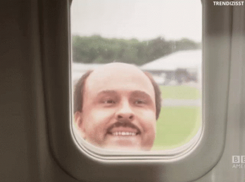 A Bald Man With A Mustache Looks Out A Window Of An Airplane GIF