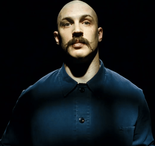 a bald man with a mustache wearing a blue shirt