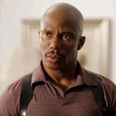 A Bald Man With A Mustache Wearing A Purple Shirt And Black Suspenders GIF