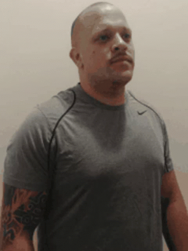 A Bald Man With A Tattoo On His Arm Is Wearing A Grey Nike Shirt GIF