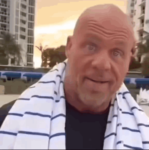 A Bald Man With A Towel Around His Neck Is Smiling . GIF