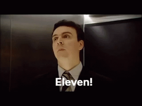 A Bald Man With Braces On His Teeth Is Looking Up At The Word Eleven GIF