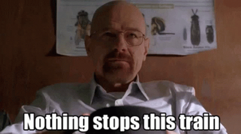A Bald Man With Glasses And A Beard Is Sitting In Front Of A Poster That Says Nothing Stops This Train . GIF