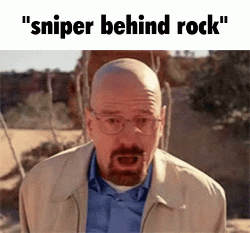 A Bald Man With Glasses And A Beard Is Standing In The Desert With The Words " Sniper Behind Rock " Written Above Him GIF