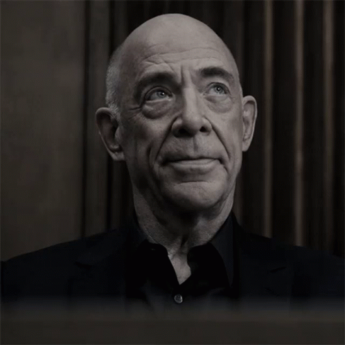 A Bald Man With His Eyes Closed And A Black Shirt GIF
