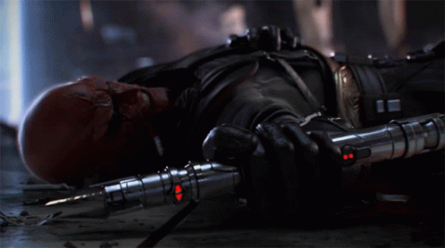 A Bald Man With Red Eyes Is Holding A Red Light Saber GIF