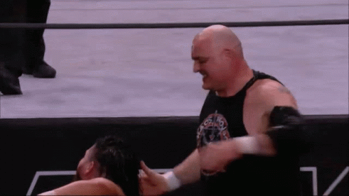 a bald wrestler is wrestling another wrestler in a ring .