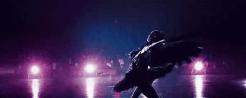 A Ballerina Is Dancing On A Stage In Front Of A Crowd In A Dark Room . GIF