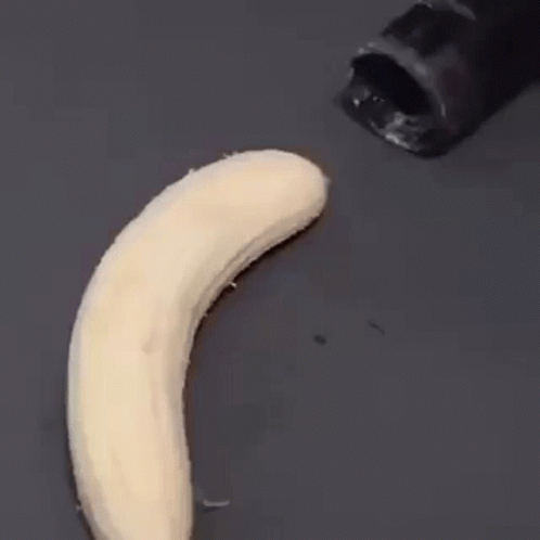 A Banana Is Being Peeled By A Black Knife On A Black Surface . GIF