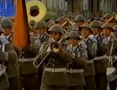A Band Of Soldiers Marching In A Parade Playing Instruments Including A Trumpet GIF