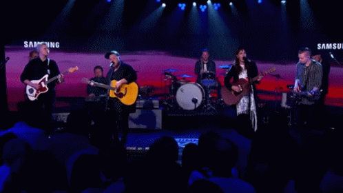 A Band Performs On Stage In Front Of A Samsung Banner GIF
