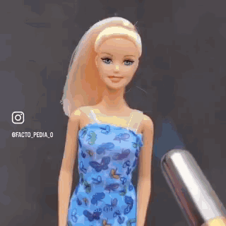 A Barbie Doll With A Burning Head Is Wearing A Blue Dress With Butterflies On It . GIF