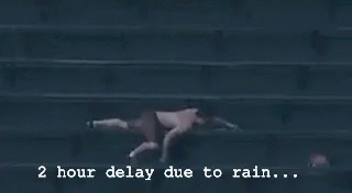a baseball game is being played in the rain and the scoreboard says 2 hour delay due to rain