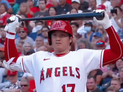 A Baseball Player For The Angels Is Holding A Bat Over His Head In A Crowded Stadium . GIF