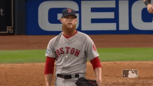a baseball player for the boston red sox stands in front of a geico sign