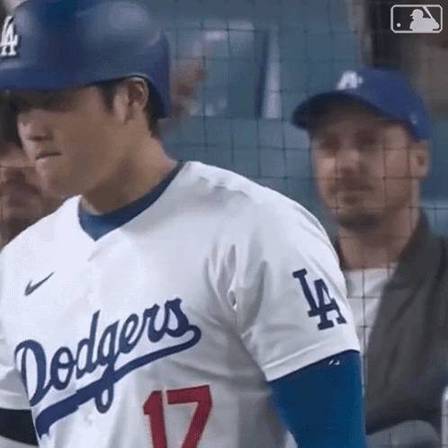 A Baseball Player For The Dodgers Is Standing In The Dugout Looking At The Camera . GIF