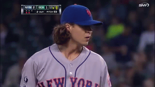 a baseball player for the new york mets stands in front of the scoreboard